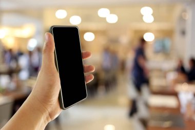 Arka kahve kafede akıllı telefon cihazı tutan bir adamın eli