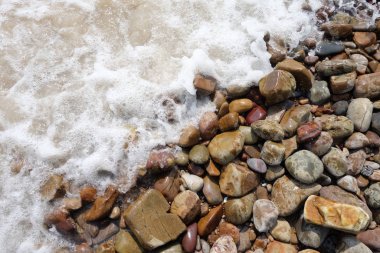 Dalgalar deniz kenarına ya da çakıllı plaj arka planına çarptı.