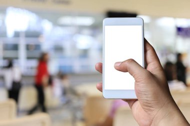 Bulanık hastane arka plan üzerinde akıllı telefon cihazı tutan bir adamın eli ve tasarım için kırpma yolları var.