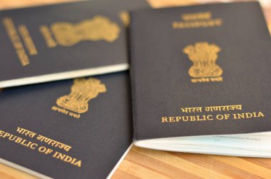 Birçok (üç) Hint pasaportu sergilenmekte olan ahşap arka planda tutuluyor. Hindistan Cumhuriyeti 'nin ulusal amblemi, Sarnath' lı Ashoka 'nın aslan başkentidir. Küresel vatandaş
