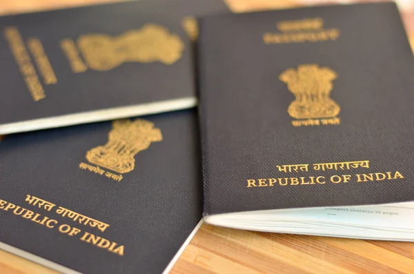 Birçok (üç) Hint pasaportu sergilenmekte olan ahşap arka planda tutuluyor. Hindistan Cumhuriyeti 'nin ulusal amblemi, Sarnath' lı Ashoka 'nın aslan başkentidir. Küresel vatandaş