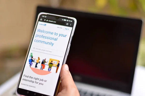 San Francisco, ABD, 2020. Android akıllı telefonunu elinde tutan kadının ofisinde Linkedin uygulamasının son versiyonu var. Arka planda odak dışı dizüstü bilgisayar var. Sosyal ağı kabul et