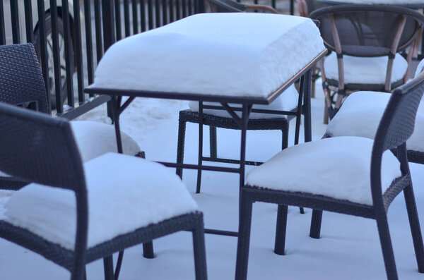 Photo of outdoor furniture, table with chairs in a restaurant patio backyard completely covered in snow in winters in north indian winters