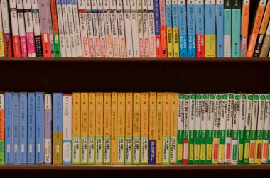 Tokyo, Japonya, 2020. Kütüphanedeki kitaplıkta Japonca yazılmış isimlerle düzenlenmiş çok kitapların yan görünümü. Konsept: Eğitim, Bilgi, Kitapçı, Ders.