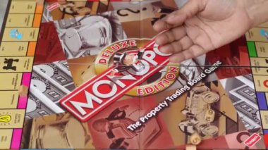 Londra, İngiltere, İngiltere, 2020. Evde Monopoly tahtasında zar atan bir oyuncu. Monopoly popüler dünya kültürünün bir parçasıdır, dünya çapında eğlenceli bir finansal eğitim oyunu olarak yerel lisanslı olarak kullanılır.