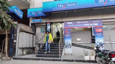 Delhi, Hindistan: 2020 Hintli genç kadın, perakende bankacılığı yapan bir müşteri, finansal krizden elde ettiği parayla Yes Bank şubesinden geliyor. Nakit para çekme sınırlamaları var.