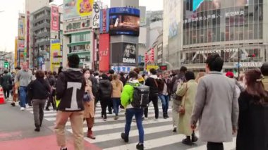 slow motion of masked people crossing at shibuya scramble