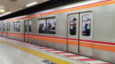 masked people in tokyo metro as it closes and goes away