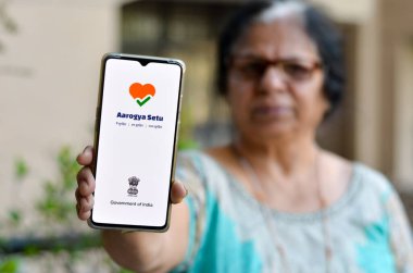 Yeni Delhi, Hindistan, 2020. Yaşlı kadın Aarogya Setu uygulamasını ev karantinasında cep telefonunda gösteriyor. Corona virüsü (Covid-19) salgınının önlenmesi ve test edilmesi için Hint govt 'u tarafından başlatılır.