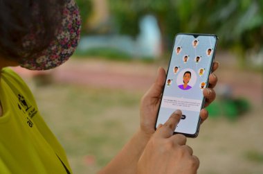 Delhi, Hindistan, 2020. Maskeli kız Aarogya Setu uygulamasını cep telefonuna karantina altına al. Corona virüsü (Covid-19) salgınının önlenmesi ve test edilmesi için Hint govt 'u tarafından başlatılır.