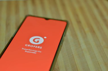 Yeni Delhi, Hindistan, 2020. Ahşap bir arka planda, Grofers uygulaması cep telefonunda açık bir şekilde yatıyordu. Corona Virüsü (Covid-19) salgınında sadece temel ihtiyaçların teslim edilmesine izin veriliyor. 