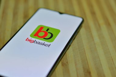 Yeni Delhi, Hindistan, 2020. Büyük Basket uygulaması cep telefonunda açık olan ahşap bir arka planda düz bir düzlem. Corona Virüsü (Covid-19) salgınında sadece temel ihtiyaçların teslim edilmesine izin veriliyor. 