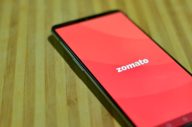 Mumbai, Maharashtra, Hindistan, 2020. Zomato Yemek Teslimat uygulaması ile ahşap bir arka planda cep telefonunda yatıyordu. Corona Virüsü süresince yiyecek teslimatını engelleme ve temel hizmetlere izin verilmektedir.