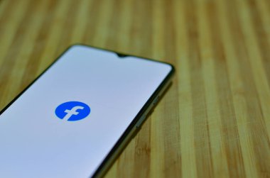 Yeni Delhi, Hindistan, 2020. Tahta bir arka planda akıllı telefondaki Facebook uygulamasının düz düzeni. Dijital Hindistan Konsepti
