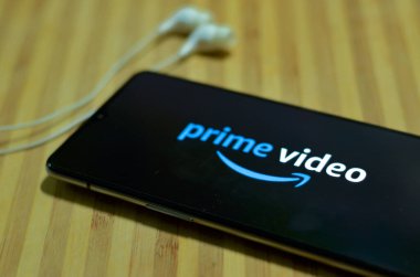 New York, ABD, 2020. Mobil ekranda kulaklıklı Amazon uygulaması açık ahşap tahta üzerinde düz bir düzen. Corona virüsü (Covid-19) salgını sırasında OTT platformlarının izlenme oranı artmıştır.