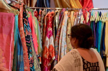 Hindistan 'ın başkenti Yeni Delhi' de Dilli Haat veya Sarojini Nagar pazarında sergilenen gözlüklü yaşlı Hintli kadın tasarım kurta (Salwar Kamiz) adlı mağazada sergileniyor.