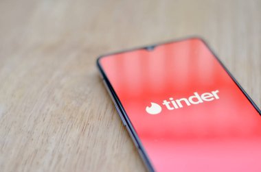 Londra, İngiltere, İngiltere, 2020. Ahşap arka planı ve Tinder uygulamasının logosu akıllı telefon ekranında sergileniyordu. Tinder çevrimiçi bir sosyal arama ve flört mobil uygulamasıdır