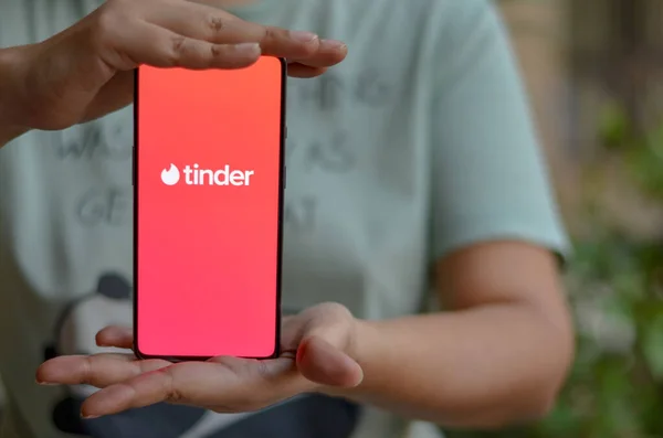 Yeni Delhi, Hindistan, 2020. Düz zeminde, tahta arka planda ve Tinder logosu akıllı telefon ekranında kadın ellerindeydi. Tinder bir sosyal arama ve flört mobil uygulamasıdır