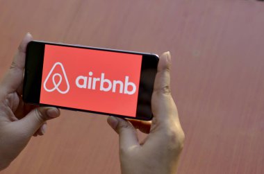 New York, ABD, 2020. Elinde cep telefonu olan bir kadın Airbnb uygulamasını ahşap arka planda gösteriyor. Airbnb, Corona Virüsü (Covid-19) salgını sırasında büyük kayıplarla karşılaştı.