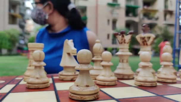 Lassú mozdulat egy sakkozó lánytól, aki arra vár, hogy az ellenfél játsszon, és izgatottan gondolkodik a következő lépésén. Maszkot visel a Corona vírus (Covid-19) világjárvány idején.. — Stock videók