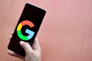 Kaliforniya, ABD, 2020. Mobil ekrandaki Google logosu, bir kadın tarafından tutulan ahşap arka planda.