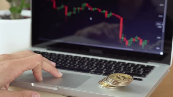 Resolución 4k de un hombre que comprueba gráfico criptomoneda y monedas de bitcoin a su lado — Vídeo de stock