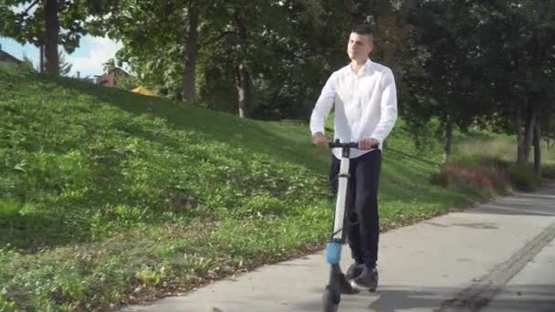 4k resolutie van jonge casual business student man paardrijden elektrische scooter op een stoep — Stockvideo