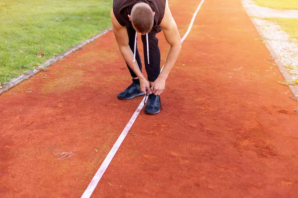 Man tying shoes on the race track — Stock Photo, Image