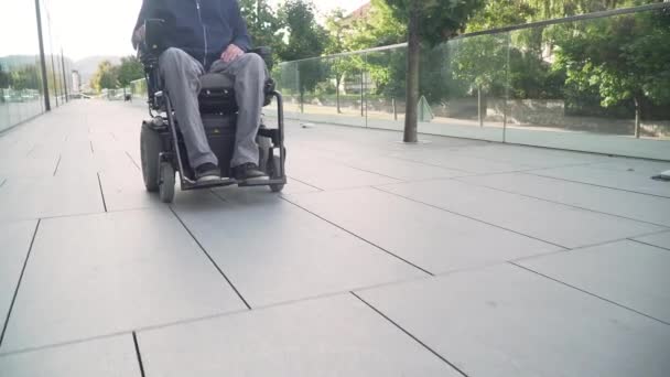 4k risoluzione primo piano seguire da davanti a un uomo sulla sedia a rotelle elettrica guida su una strada. Concetto di accessibilità — Video Stock