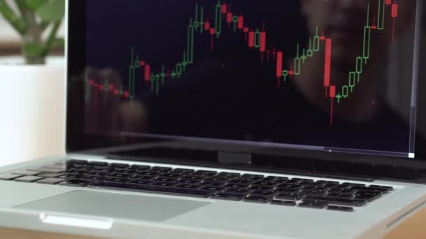 4k resolutie van een man spelen met Bitcoin munten, tellen ze met cryptogeld grafiek op een laptop — Stockvideo