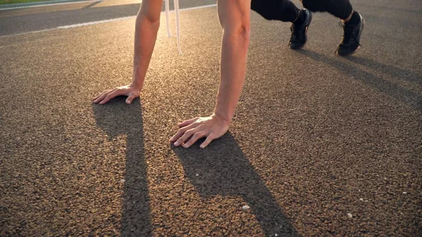 Giovane uomo in forma facendo flessioni al mattino all'aperto su strada al tramonto con forte bagliore di sole — Foto Stock