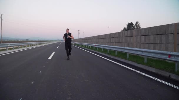 4k video di giovane uomo in forma che corre più vicino alla fotocamera esausta, all'aperto sulla strada vuota — Video Stock