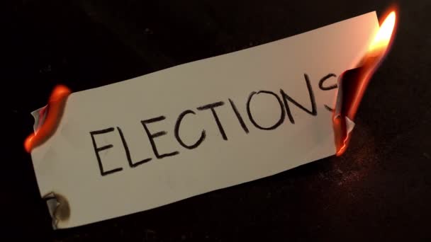 Εκλογές γραμμένο σε λευκό χαρτί εγκαύματα. Φωτιά με καπνό και στάχτες σε μαύρο φόντο — Αρχείο Βίντεο
