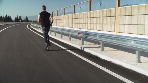 4k следите за видео, как молодой человек в спортивной форме бегает на улице по пустой улице — стоковое видео