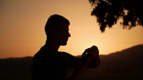 Sillhouette de un hombre tocando y comprobando el smartwatch en la puesta del sol hermosa en el fondo — Vídeos de Stock