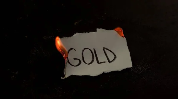 Arany szó, fehér papírra írva. Tűz füsttel és hamuval fekete háttéren — Stock Fotó