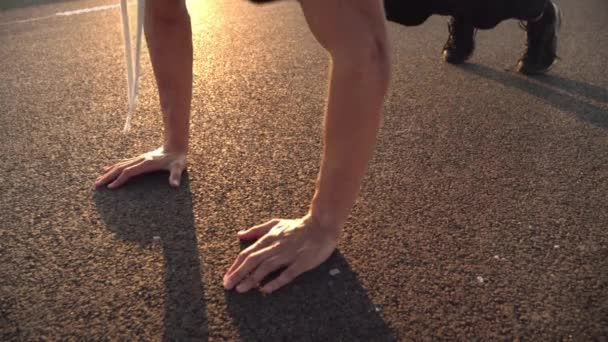 4k todavía video de hombre en forma joven haciendo flexiones en la noche al aire libre en la carretera al atardecer con fuerte resplandor solar — Vídeos de Stock