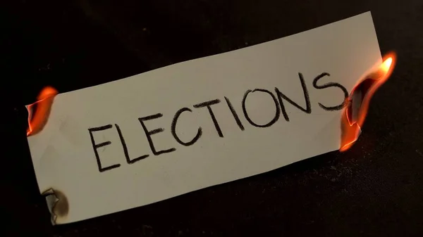 Le elezioni parola scritta su carta bianca brucia. Fuoco con fumo e cenere su sfondo nero — Foto Stock