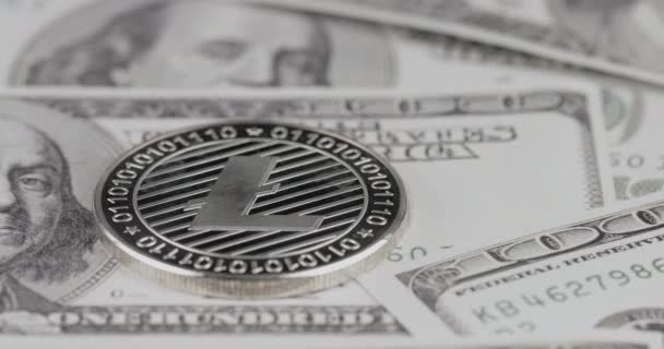 4k resolution of a cryptocurrency silver Litecoin coin on a hundred usd dollars bills. Close-up, macro shot - slider movement — Stock Video