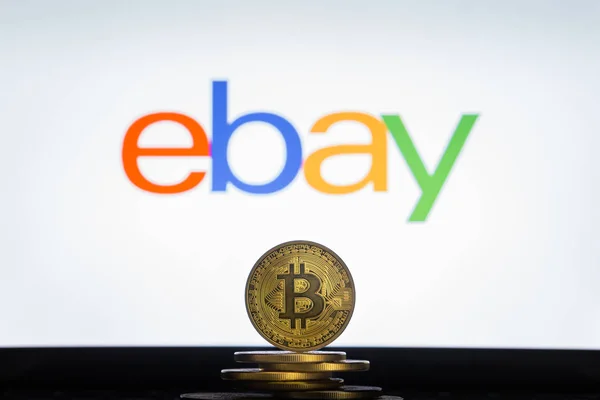 Логотип Ebay на экране компьютера со стопкой криптокурентных монет Bitcoin . — стоковое фото