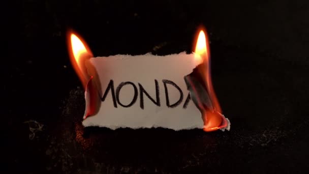 Pazartesi günü beyaz kağıda yazılmış kelime yanar. Siyah arka planda duman ve küllerle ateş — Stok video