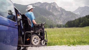 man on wheelchair going out of a car on electric lift specialized vehicle for people with disabilities. Self help for disabled people concept