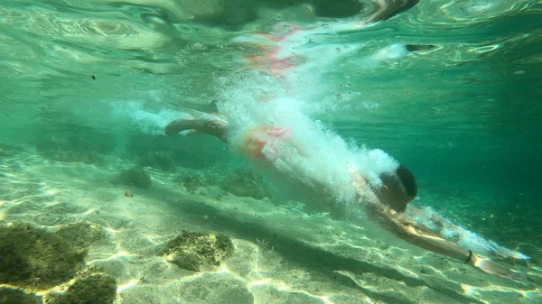 Jonge student fit mannelijke sprong in het water en is het hebben van plezier in de zomer — Stockfoto