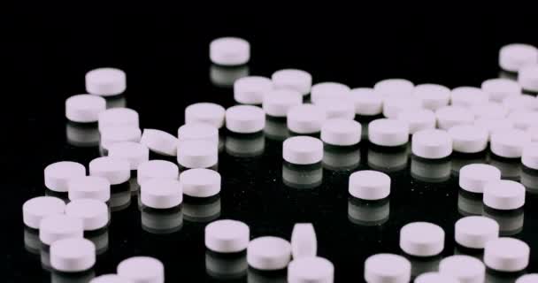 Пан движение белых таблеток на черном фоне — стоковое видео