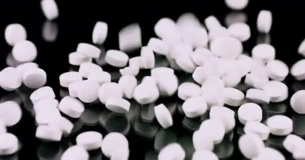 White medical pills falling on a black background — Stockvideo