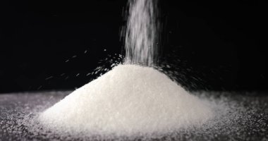 Sugar falling on a table on black background