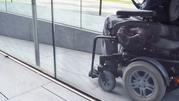 Człowiek na elektrycznym wózku inwalidzkim jadący ulicą. Koncepcja dostępności — Zdjęcie stockowe