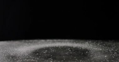 Siyah arkaplanda masaya düşen şeker ya da tuz