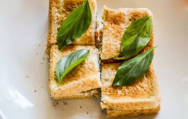 Peynirli tost ve beyaz tabakta fesleğen yaprağı. en üstteki görünüm.