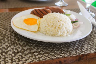 Yumurta, salatalık, domates ve salata ile birlikte beyaz tabakta domuz etli pilav, Tayland yemeği..
